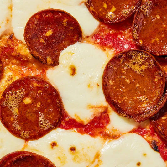 A closeup of a pizza with tomato sauce, melted mozzarella, and Prime Roots Pepperoni slices
