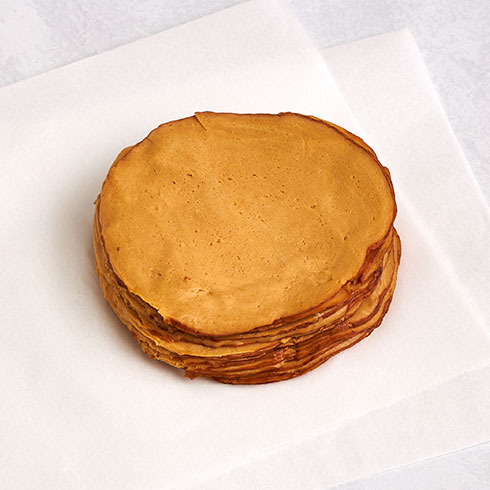 A stack of Tofurky Hickory Smoked Deli Slices on a white sheet of parchment paper
